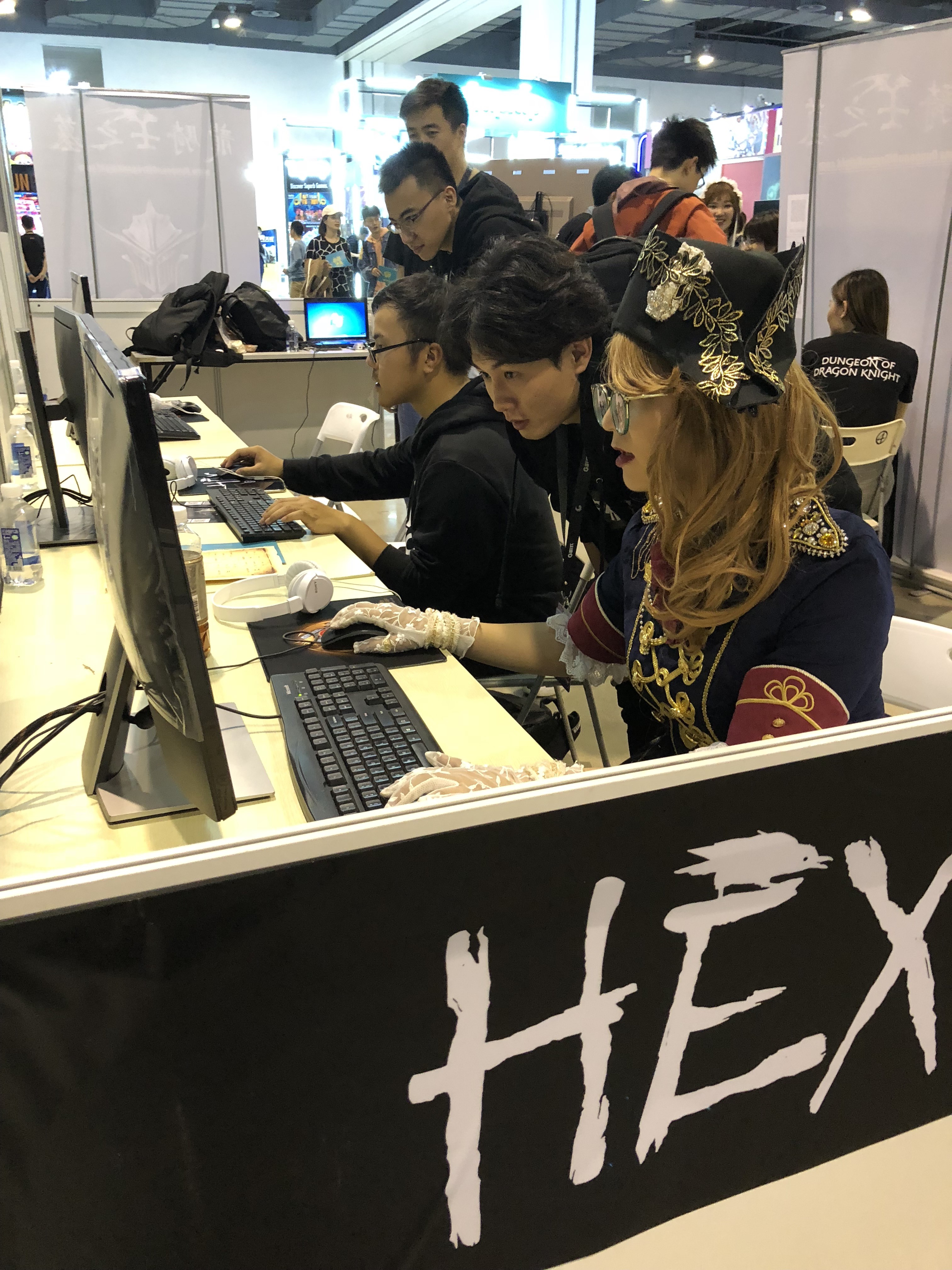 Visitors trying games at exhibition booths, with people blurred